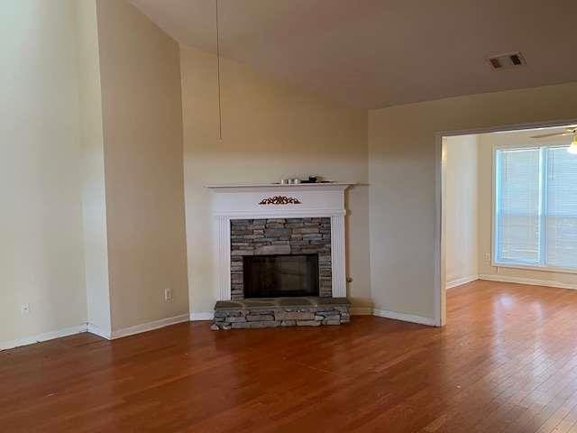 unfurnished living room with wood finished floors, baseboards, a fireplace, and visible vents