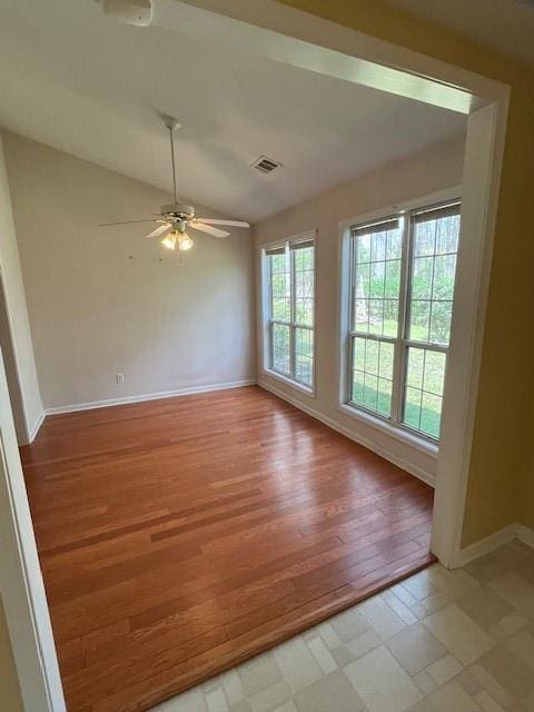 empty room with vaulted ceiling, a ceiling fan, light wood-type flooring, baseboards, and visible vents