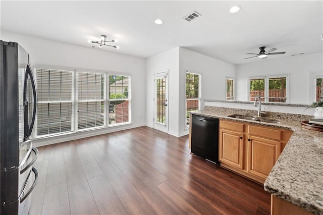 kitchen with black appliances, a sink, dark wood-style flooring, recessed lighting, and light stone countertops