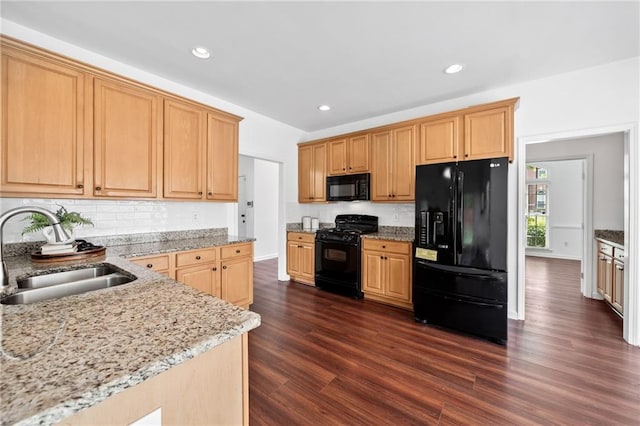kitchen featuring black appliances, a sink, dark wood-style flooring, light stone counters, and recessed lighting