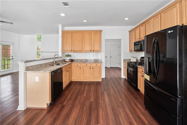 kitchen with black appliances, a peninsula, light brown cabinets, dark wood-type flooring, and recessed lighting