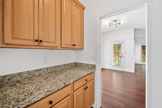kitchen with wood finished floors, light stone counters, and baseboards