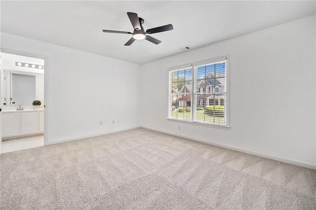 carpeted empty room featuring baseboards, ceiling fan, and a sink