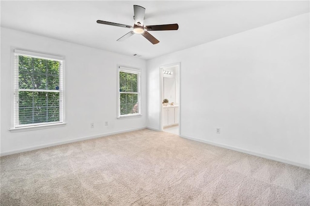 carpeted spare room featuring a ceiling fan and baseboards