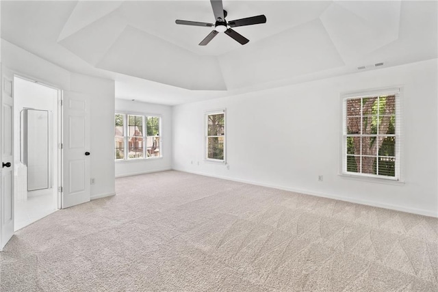 carpeted spare room with a raised ceiling, a ceiling fan, and baseboards