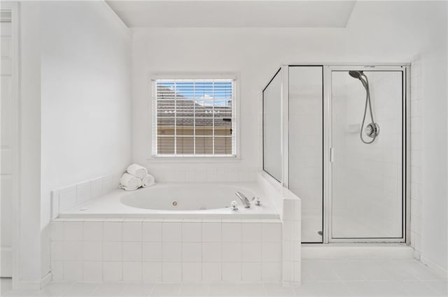 bathroom featuring a stall shower, a tub with jets, and tile patterned floors