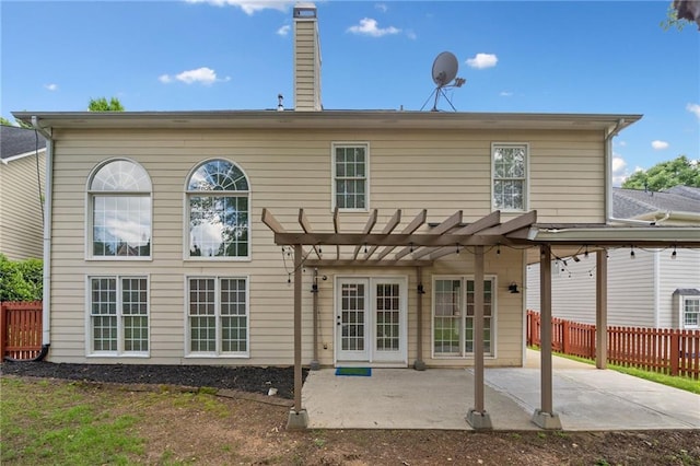 rear view of house featuring a pergola, a patio area, fence, and a chimney