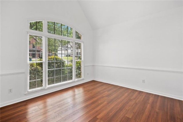empty room featuring healthy amount of natural light, wood finished floors, baseboards, and high vaulted ceiling