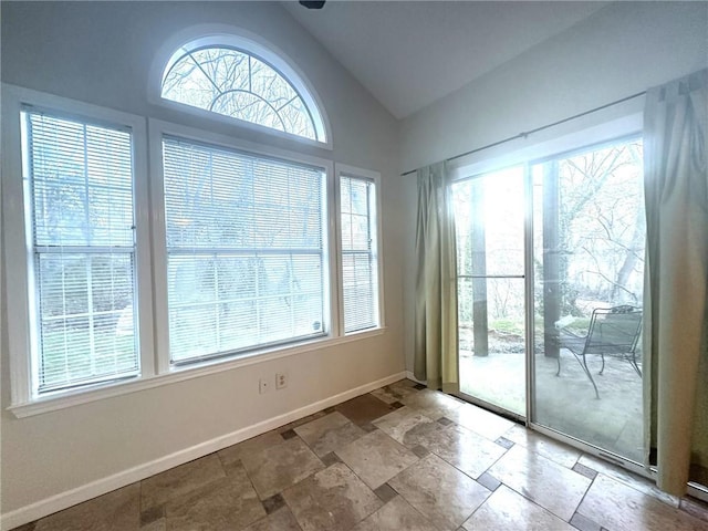 doorway featuring stone finish flooring, vaulted ceiling, and baseboards