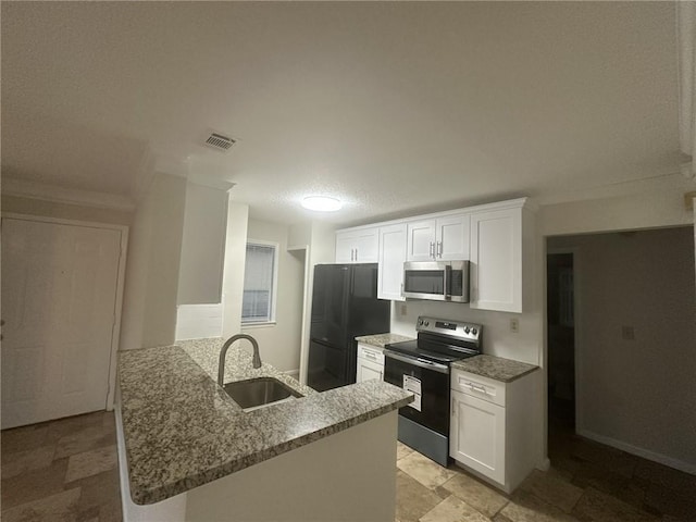 kitchen featuring electric stove, stainless steel microwave, freestanding refrigerator, a sink, and a peninsula