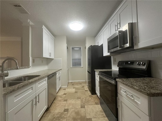 kitchen with stainless steel appliances, a sink, visible vents, white cabinetry, and dark stone counters