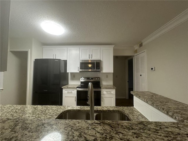 kitchen featuring appliances with stainless steel finishes, white cabinets, and light stone counters