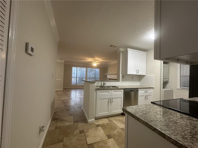 kitchen featuring stone tile floors, stacked washer and clothes dryer, ornamental molding, a sink, and stainless steel dishwasher