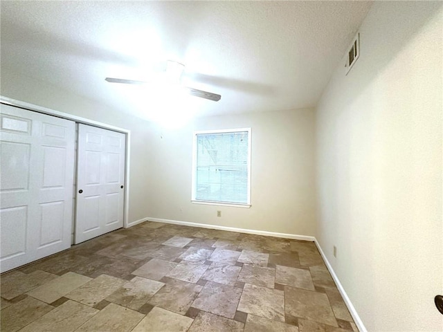 unfurnished bedroom with visible vents, baseboards, ceiling fan, stone finish flooring, and a closet