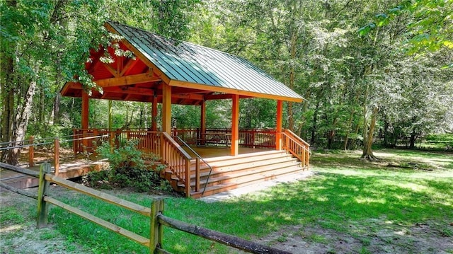 exterior space featuring a forest view, a lawn, a deck, and a gazebo