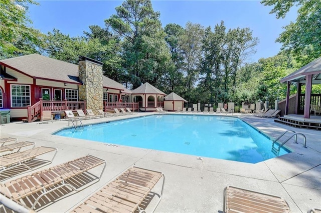 community pool featuring a wooden deck, fence, and a patio