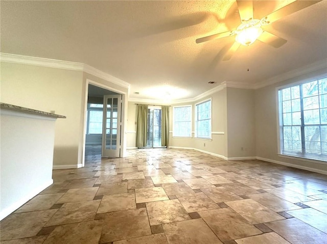 empty room with ceiling fan, baseboards, crown molding, and stone finish flooring