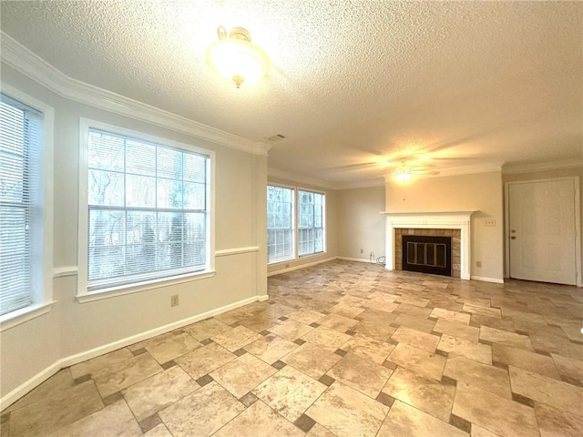 unfurnished living room with ornamental molding, a glass covered fireplace, a textured ceiling, and baseboards