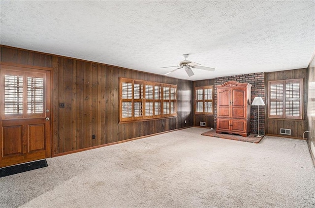 unfurnished living room featuring visible vents, carpet flooring, and a wealth of natural light