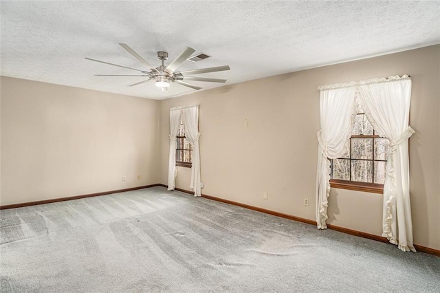 carpeted empty room with visible vents, ceiling fan, a textured ceiling, and baseboards