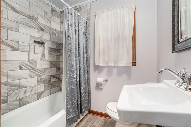 full bath featuring shower / bath combination with curtain, toilet, a sink, wood finished floors, and baseboards