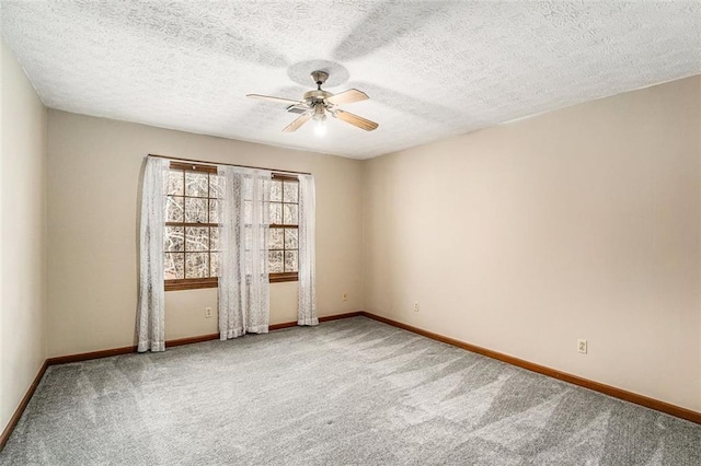 carpeted empty room featuring ceiling fan, a textured ceiling, and baseboards