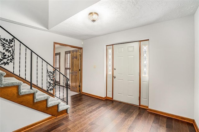 foyer entrance featuring stairway, a textured ceiling, baseboards, and wood finished floors