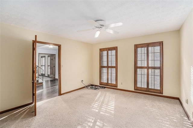 carpeted spare room featuring a ceiling fan, a textured ceiling, and baseboards