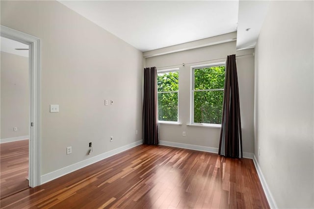 spare room with hardwood / wood-style floors and baseboards