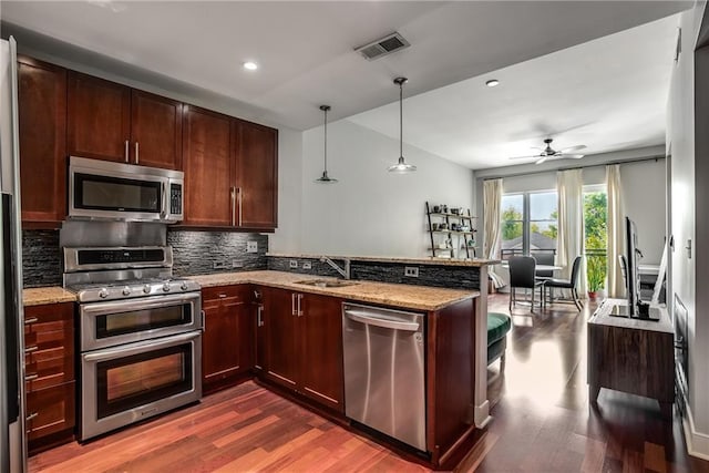 kitchen featuring appliances with stainless steel finishes, visible vents, a sink, and light stone countertops