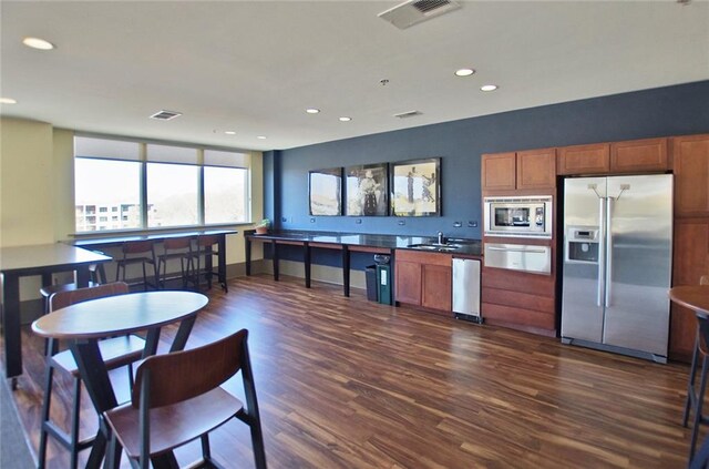 kitchen featuring appliances with stainless steel finishes, a warming drawer, a sink, dark wood-style flooring, and recessed lighting
