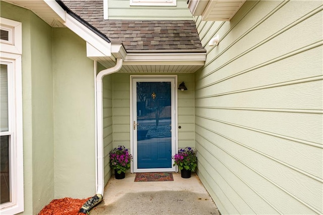 doorway to property with roof with shingles