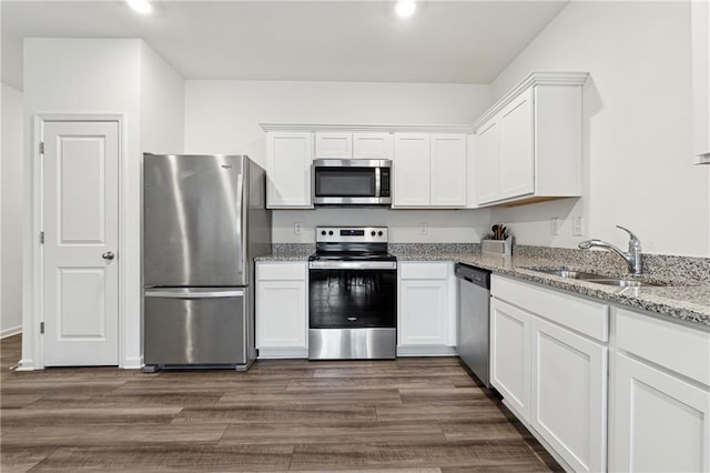 kitchen with light stone countertops, appliances with stainless steel finishes, dark hardwood / wood-style floors, and white cabinetry