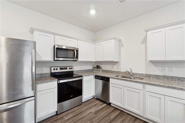 kitchen with sink, stainless steel appliances, light stone counters, dark hardwood / wood-style floors, and white cabinets