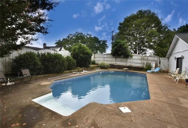 view of pool with a diving board and a patio