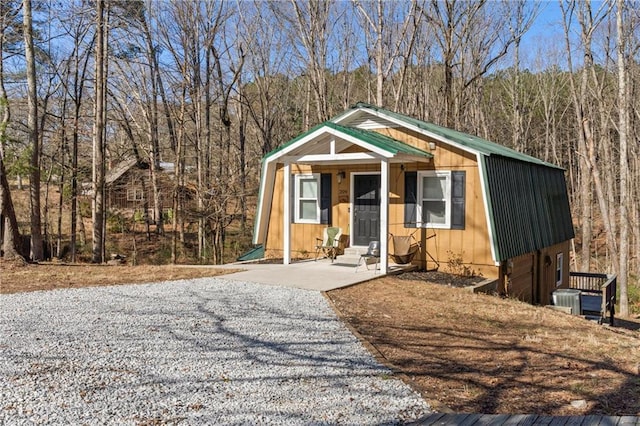 view of front of home with entry steps, metal roof, a gambrel roof, and a view of trees