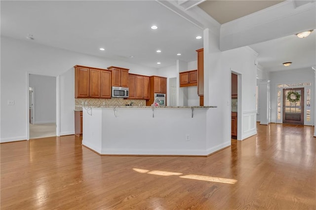 kitchen featuring brown cabinets, a peninsula, appliances with stainless steel finishes, and a breakfast bar