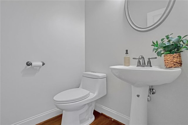 half bath featuring toilet, baseboards, and wood finished floors