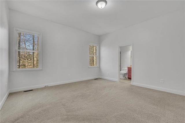 empty room featuring light carpet, visible vents, and baseboards