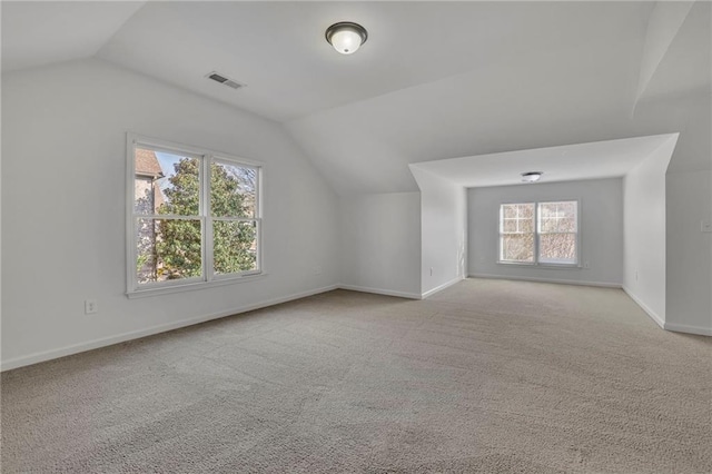 bonus room featuring lofted ceiling, baseboards, visible vents, and light colored carpet