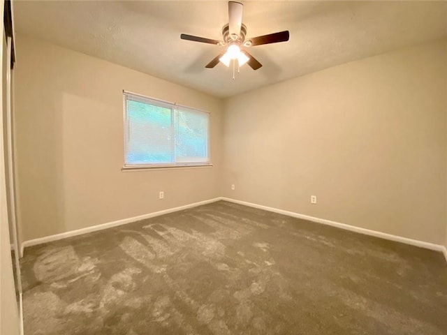 spare room with dark colored carpet and ceiling fan