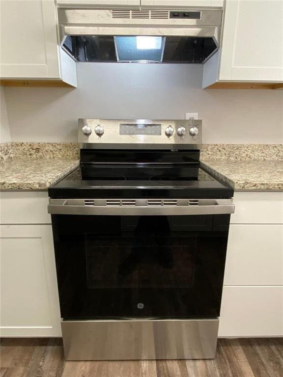 kitchen with wood-type flooring, stainless steel electric range, and white cabinets