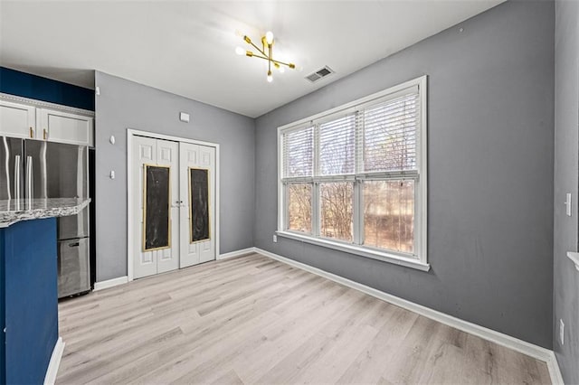 interior space featuring light wood finished floors, baseboards, visible vents, and freestanding refrigerator