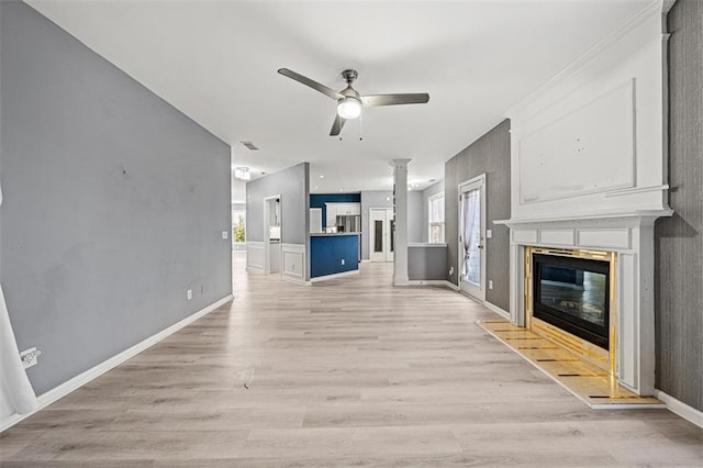 unfurnished living room featuring light wood finished floors, baseboards, a ceiling fan, and a glass covered fireplace