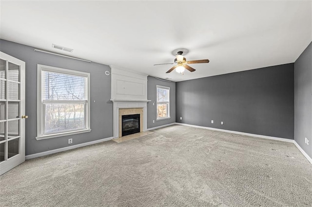 unfurnished living room featuring a fireplace, a ceiling fan, visible vents, baseboards, and carpet