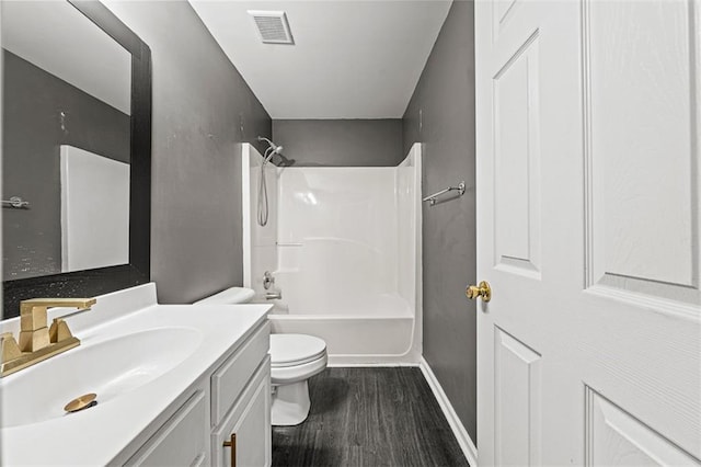 full bath with visible vents, toilet, washtub / shower combination, vanity, and wood finished floors