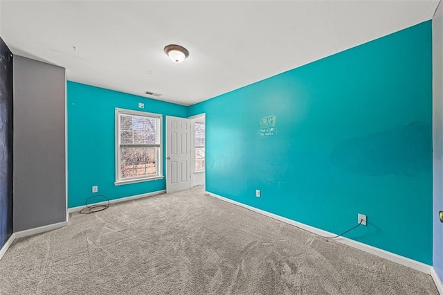 spare room with carpet flooring, visible vents, and baseboards