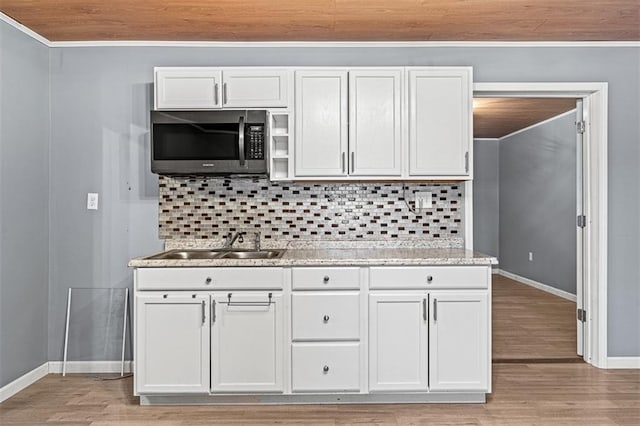 kitchen with wood ceiling, stainless steel microwave, a sink, and backsplash