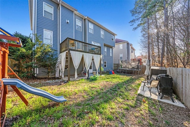 rear view of house featuring a patio, a fenced backyard, a trampoline, a yard, and a playground