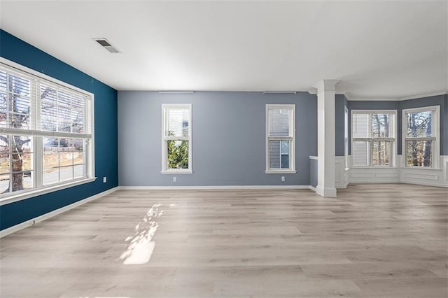 unfurnished living room featuring baseboards, visible vents, light wood finished floors, and ornate columns